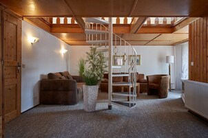 Una sala de estar acogedora con una escalera de caracol, paredes de madera y una gran planta en maceta.