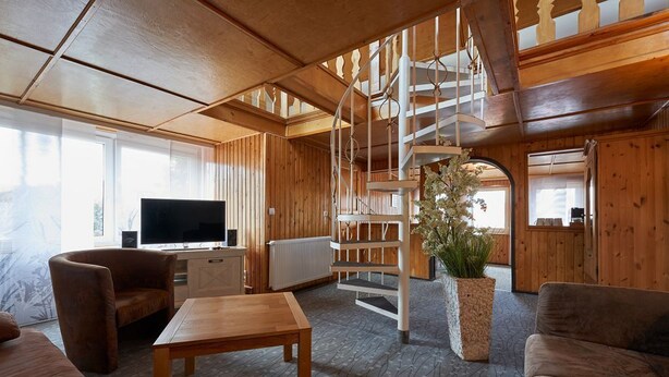A wooden interior with a spiral staircase, a TV, and a sofa. - Hotel Schlossblick (Wernigerode)