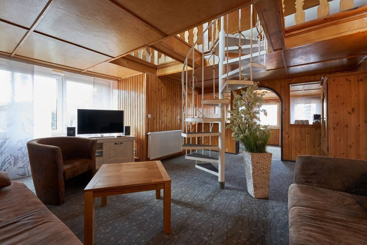 Un interior de madera con una escalera de caracol, un televisor y un sofá.