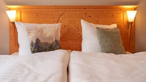 A double bed with two pillows, one with a forest design and another with a geometric pattern. - Hotel Schlossblick (Wernigerode)