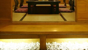 A traditional Japanese-style room with tatami mat flooring, a low table with cushions, and a low wooden bench. - Herald Suites (Makati)