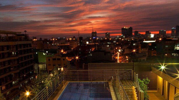 A rooftop pool with a cityscape view at dusk. - Herald Suites (Makati)