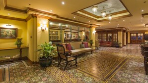 A spacious lobby with a patterned floor, a sofa, chairs, and a large mirror. - Herald Suites (Makati)