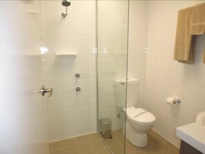 Un baño con cabina de ducha de vidrio, inodoro y lavabo.