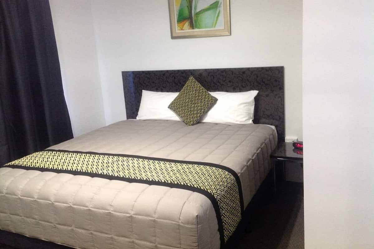 A hotel room with a bed, a nightstand, a lamp, and a painting on the wall.