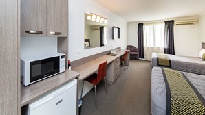 A hotel room with a kitchenette, a bed, a desk with a chair, a mirror, and a TV. - Burke and Wills Motor Inn (Kingaroy)