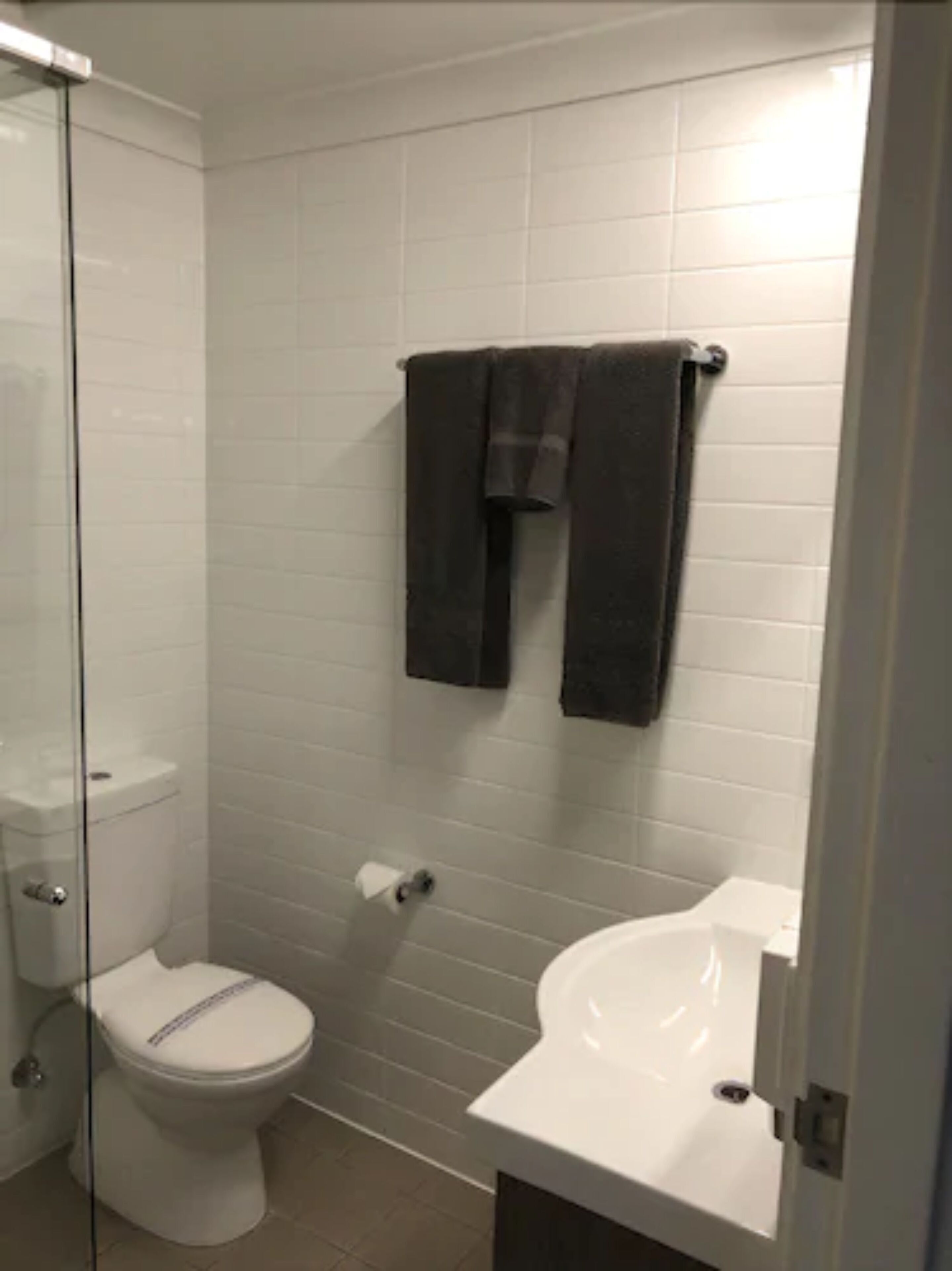 Une salle de bain équipée de toilettes, d’un lavabo et d’une douche à parois en verre.