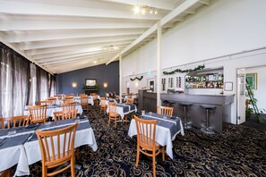 Un restaurant doté de nombreuses tables et chaises, d’un bar et d’un tapis à motifs.