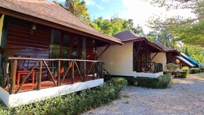 A row of wooden cabins with balconies, surrounded by gravel paths and greenery. - Saithong Resort (Sikao)