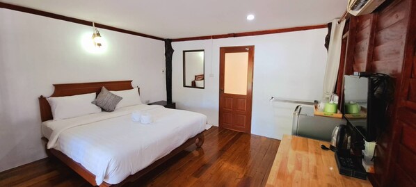 A bedroom with a wooden bed, a wooden desk, a mirror, and a door. - Saithong Resort (Sikao)