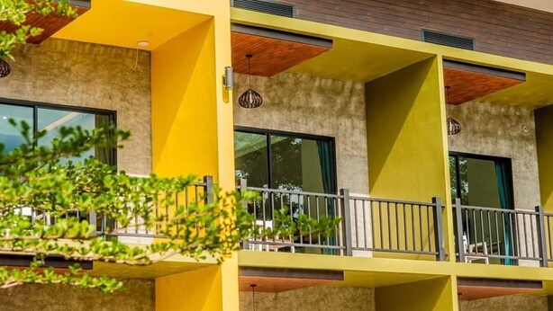 A multi-story building with a yellow facade, large windows, and balconies. - Saithong Resort (Sikao)