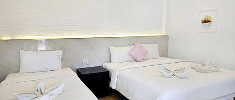 A hotel room with two beds, white bedding, a nightstand, an air conditioning unit, and a small wall-mounted decoration.