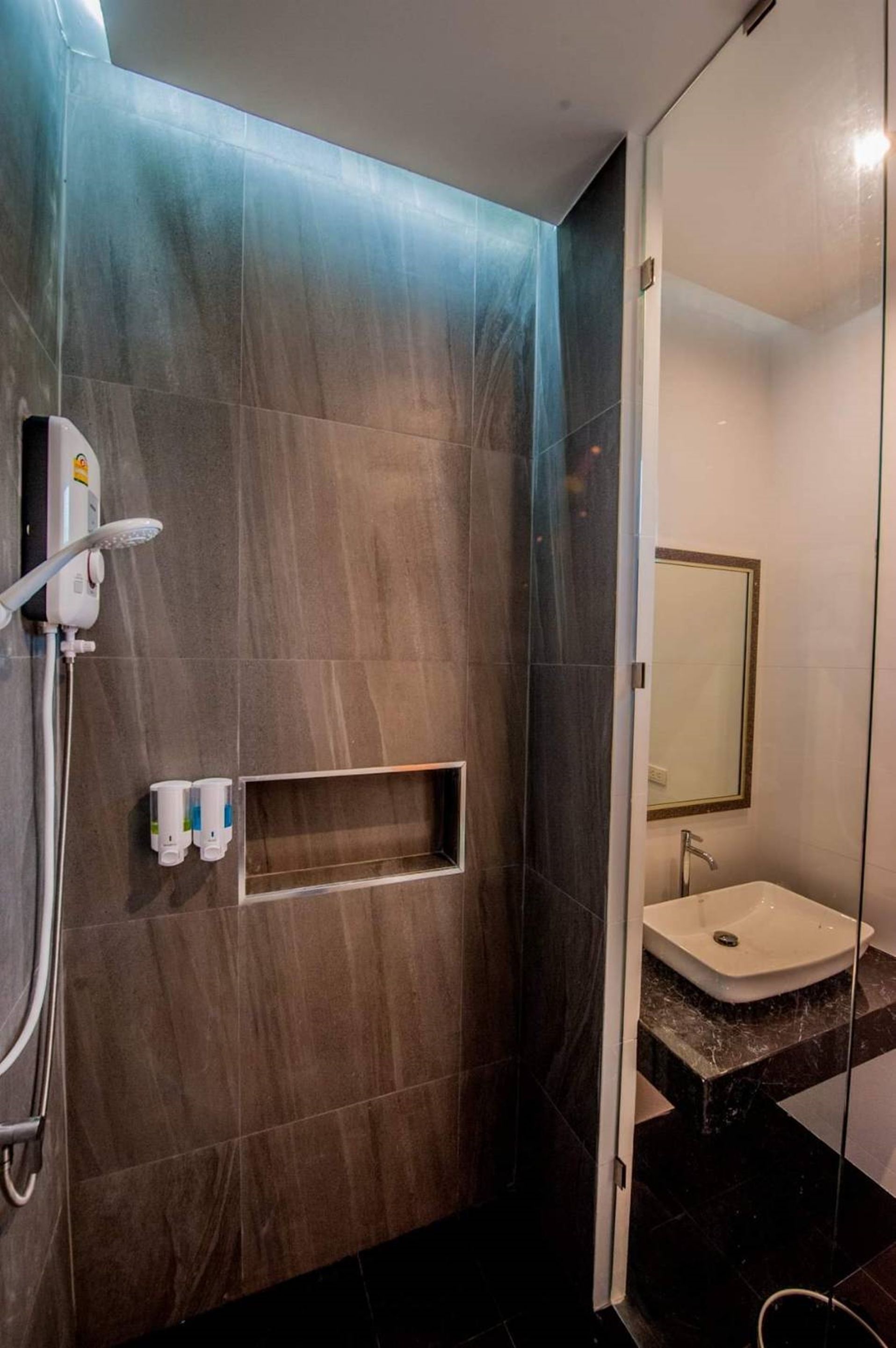 A modern bathroom with dark tiles, a built-in sink, and a shower area.