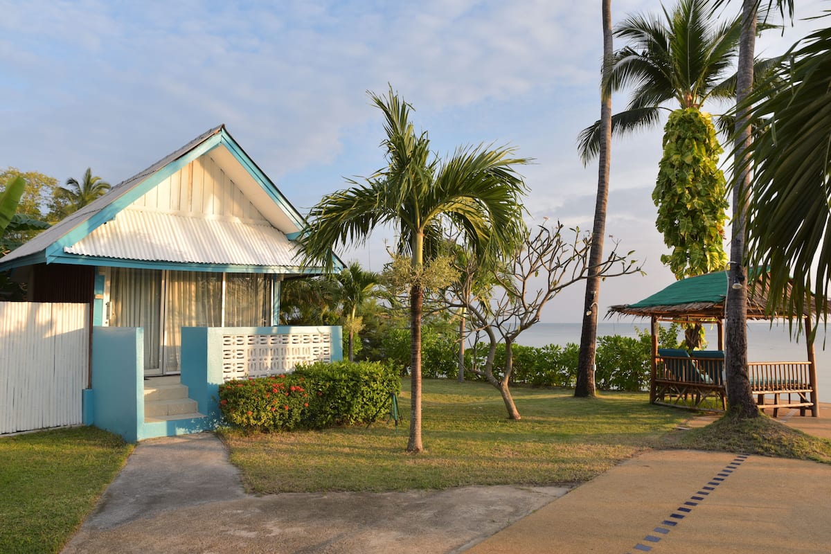 A house with a blue roof, a small porch, and a pathway leading to the entrance.