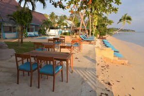 A beachside resort with a pool area, lounge chairs, and wooden tables with blue cushions. - Blu' Beach Bungalows (Koh Samui)