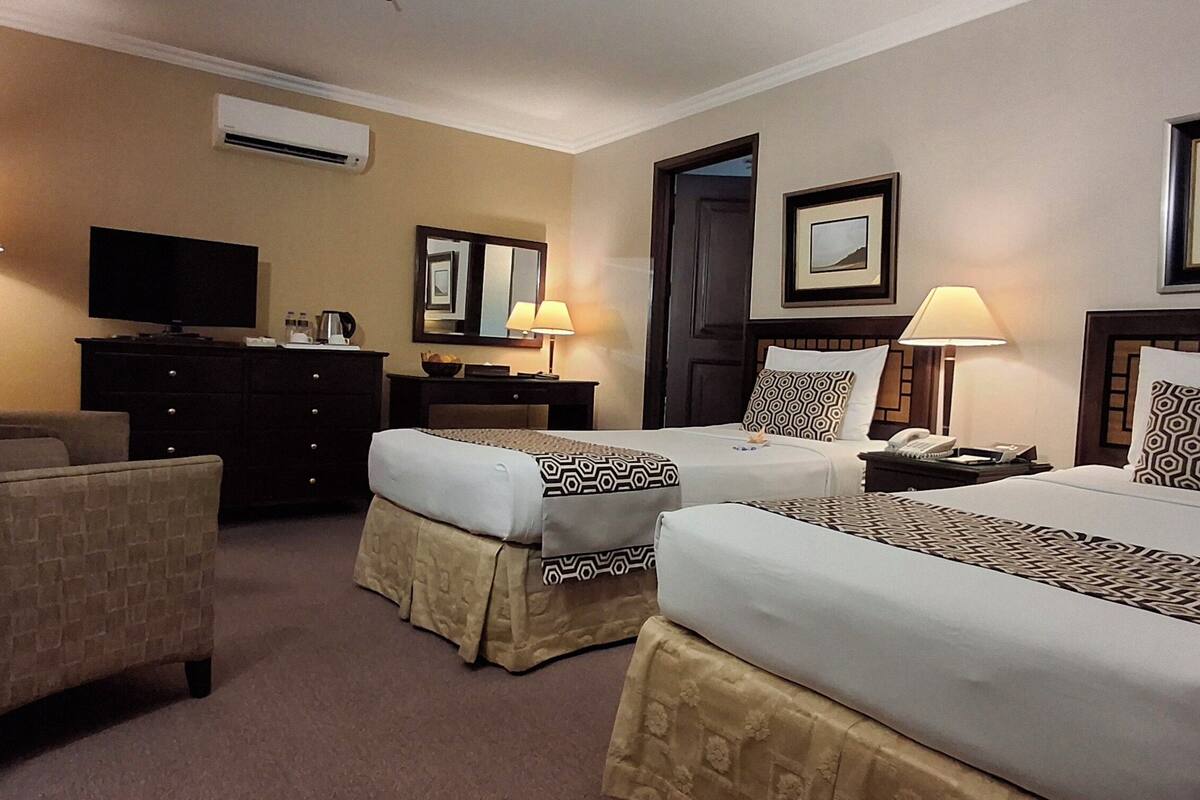 A hotel room with two beds, a TV, a desk, and a chair.