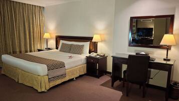 A hotel room with a bed, bedside tables, a desk, and a chair.