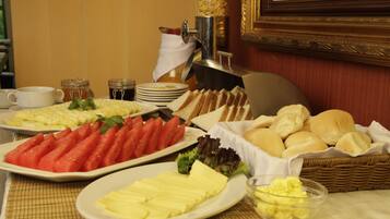 A buffet with various food items including bread, butter, and fruits.