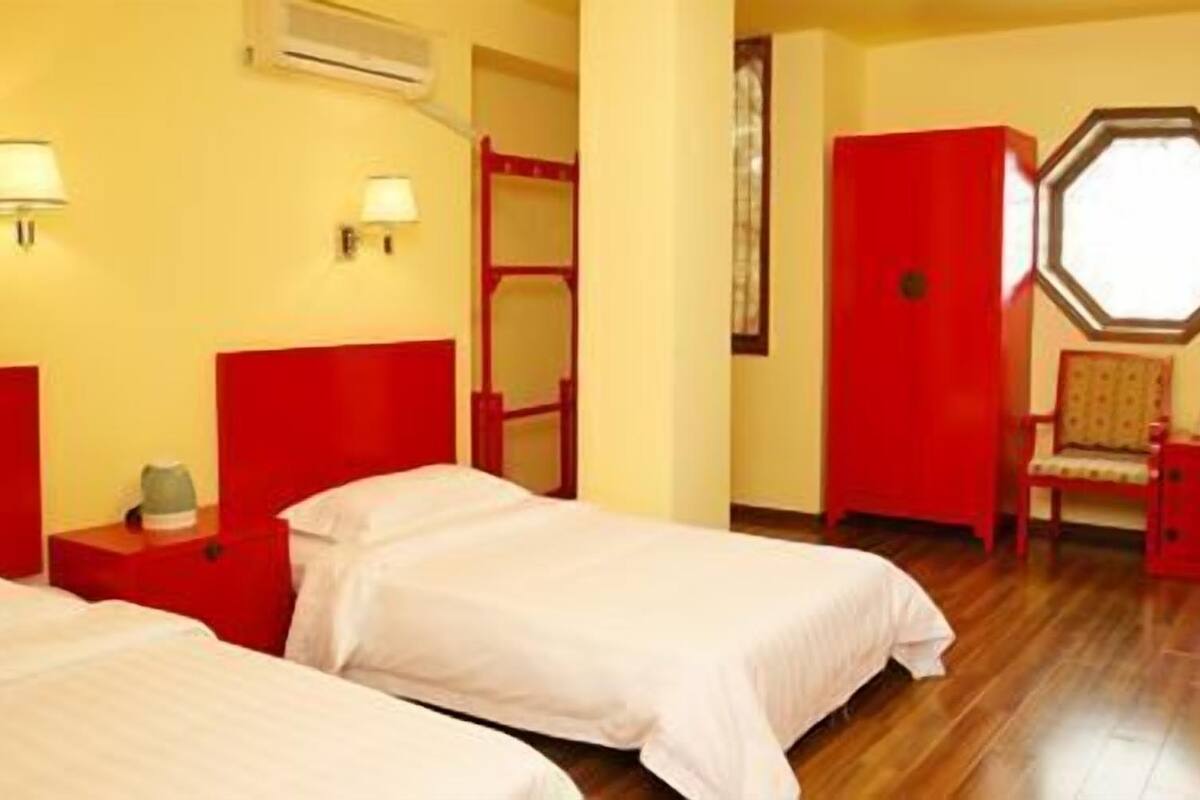 Habitació d'hotel amb dos llits, televisió, una cadira i una finestra.