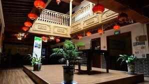 Un vestíbulo de estilo tradicional con suelo de madera, un mostrador de recepción central y plantas en macetas.