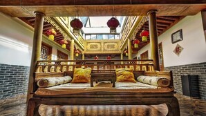 Una cama de madera tradicional con dosel, decoraciones murales ornamentales y faroles colgantes.