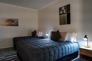 A bedroom with two beds, a nightstand, a lamp, and artwork on the walls. - Campbelltown Colonial Motor Inn (Sydney)