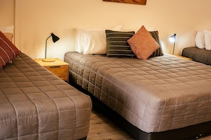 A bedroom with two beds, a nightstand, a lamp, and a painting on the wall. - Campbelltown Colonial Motor Inn (Sydney)