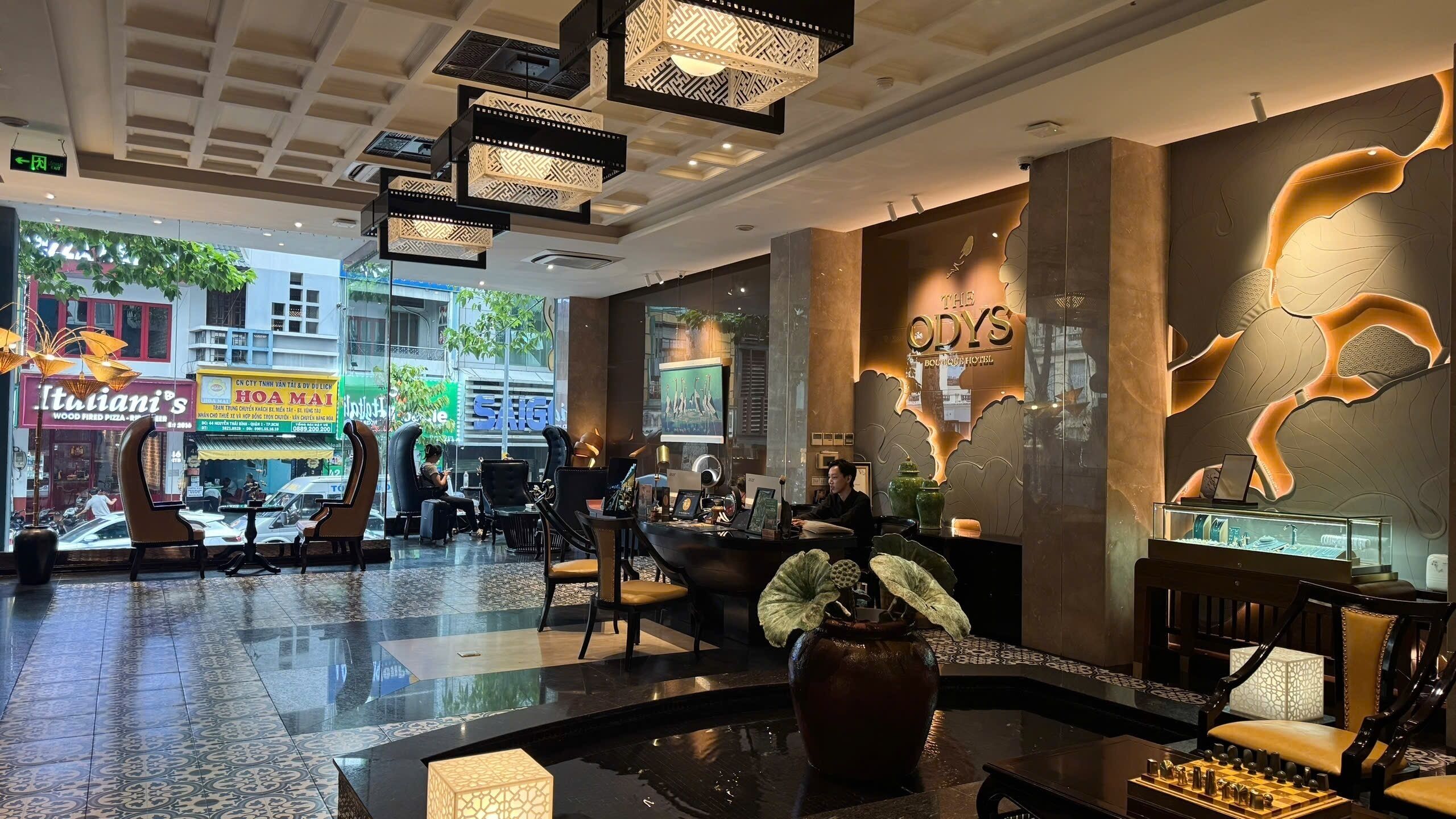 A hotel lobby with a reception desk, seating area, and a decorative fountain.