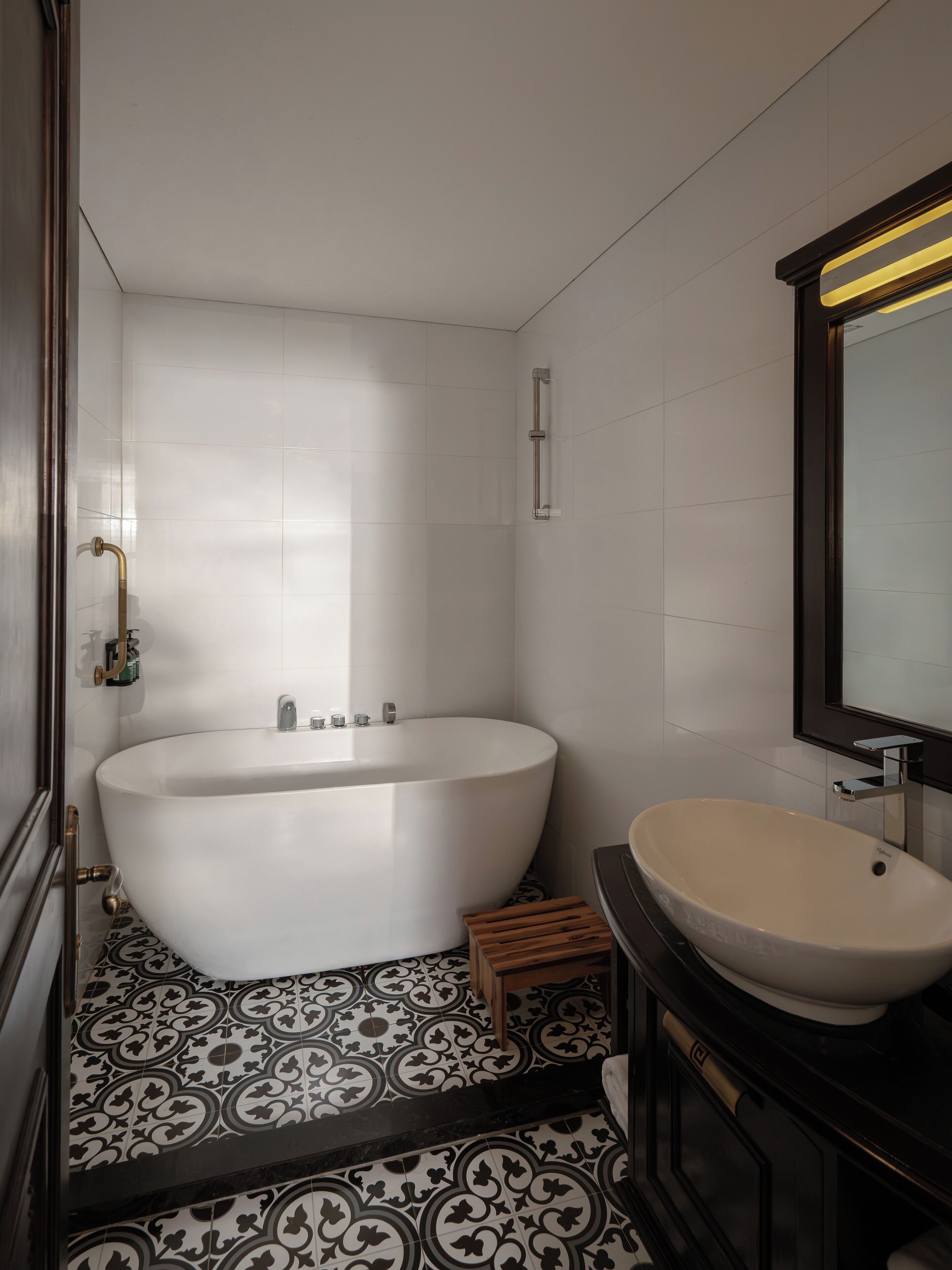 A modern bathroom with a freestanding bathtub, a vanity with a sink, and patterned floor tiles.