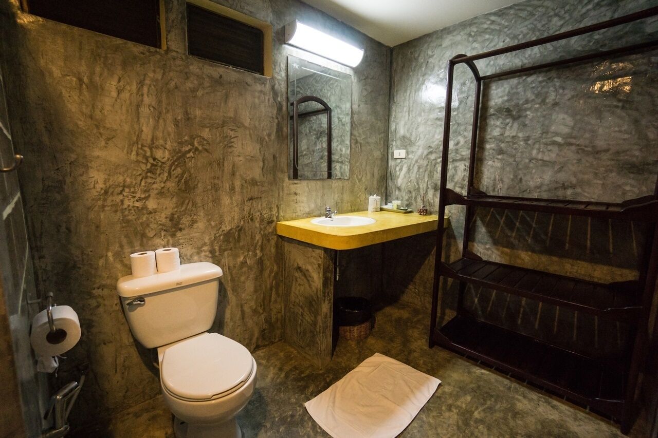 A bathroom with a toilet, sink, mirror, and shower area.