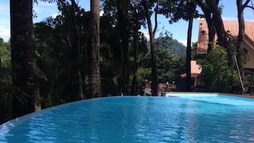 Een buitenzwembad, ligstoelen bij het zwembad