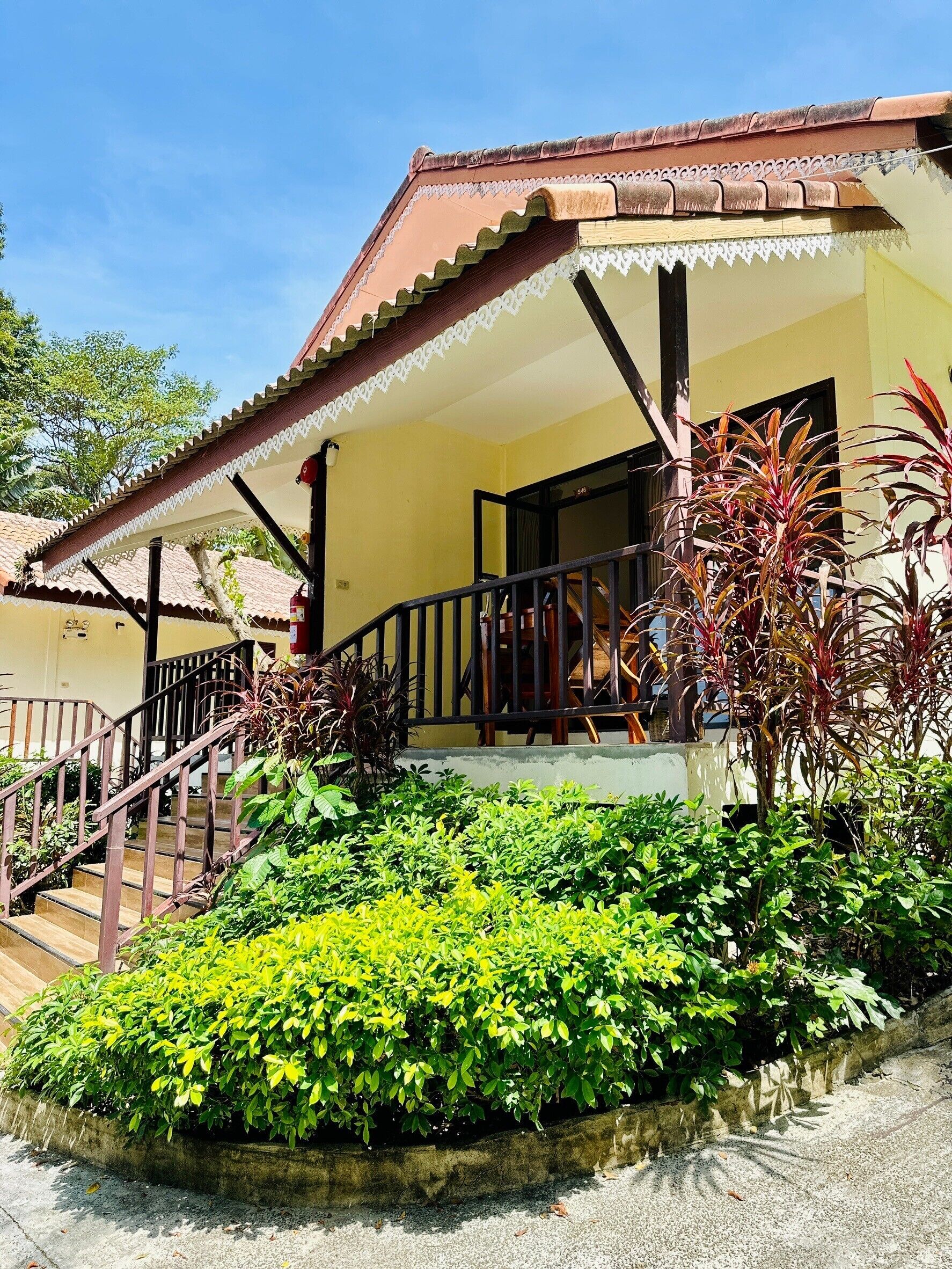 Ein Gebäude mit einer Veranda, einer Treppe und einem Garten mit verschiedenen Pflanzen.