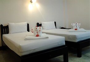 Two single beds with white linens and a small decorative item on each.