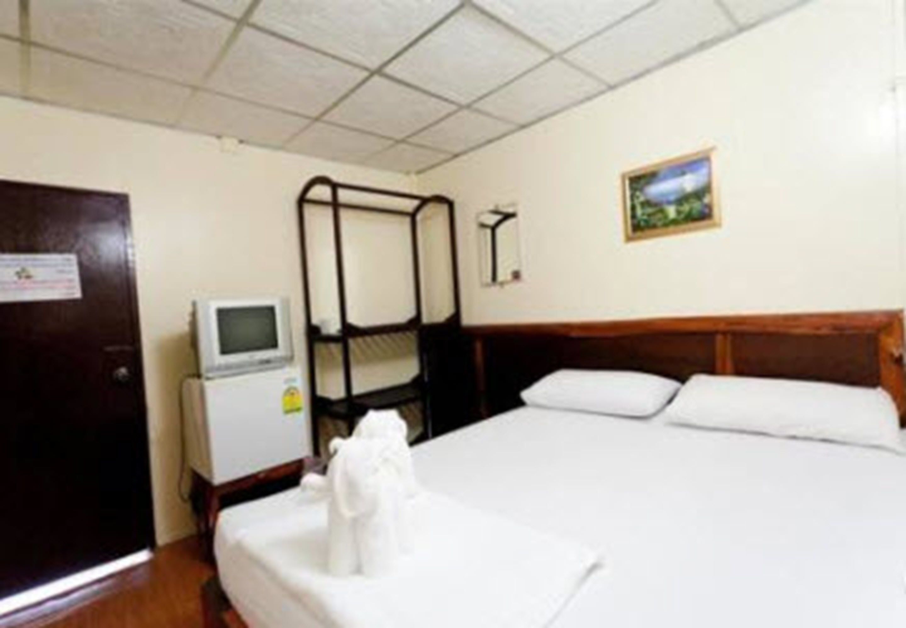 A hotel room with a bunk bed, a small desk with a computer, a television, and a framed picture on the wall.