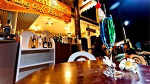 Baarissa on neonvalomainos, pulloja ja pöydällä on cocktail-lasi.