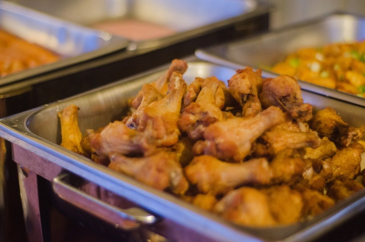 A buffet with various dishes, including fried chicken wings and other prepared foods.