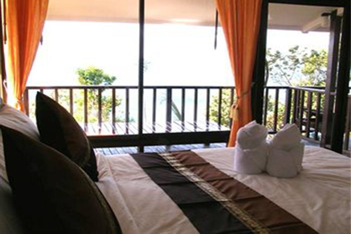 A hotel room with a bed, curtains, and a balcony with a railing.