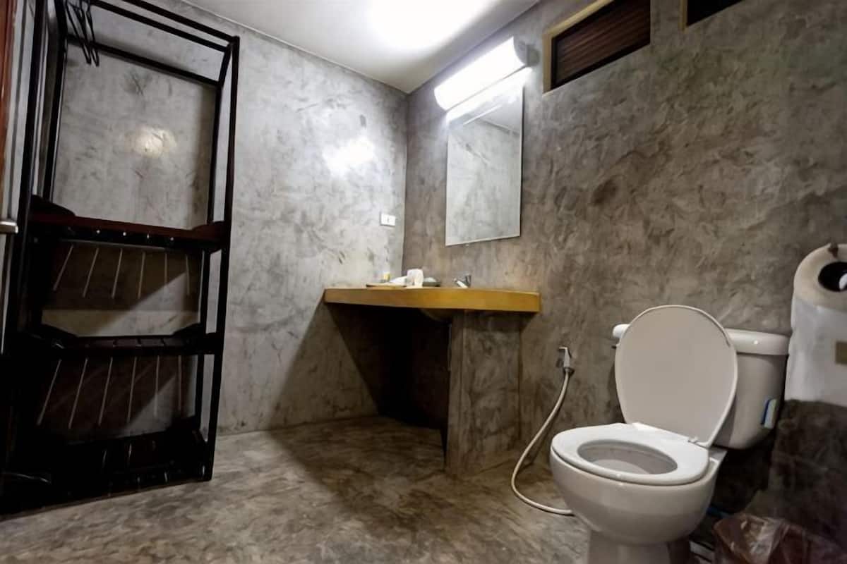A bathroom with a marble floor, a wooden shelf, a sink, a toilet, and a mirror.
