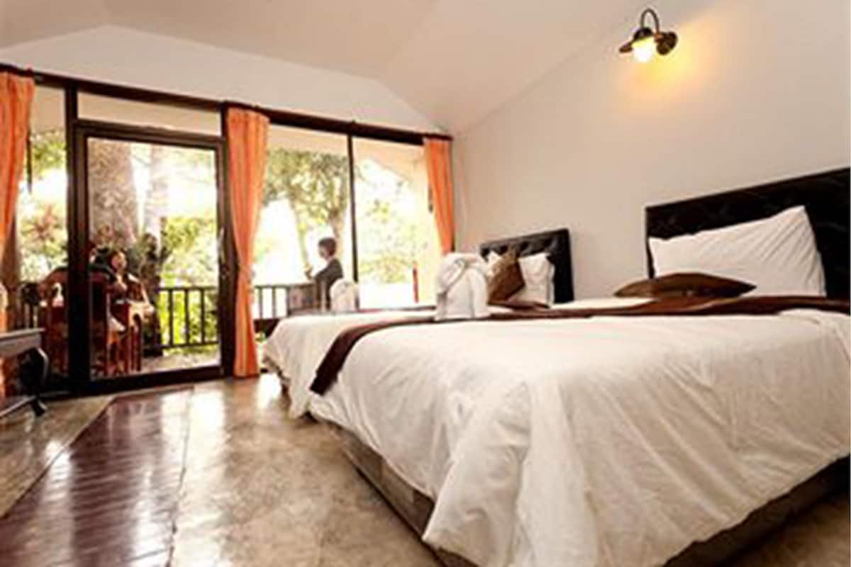 A bedroom with a large bed, a window with curtains, and a view of the outdoors.
