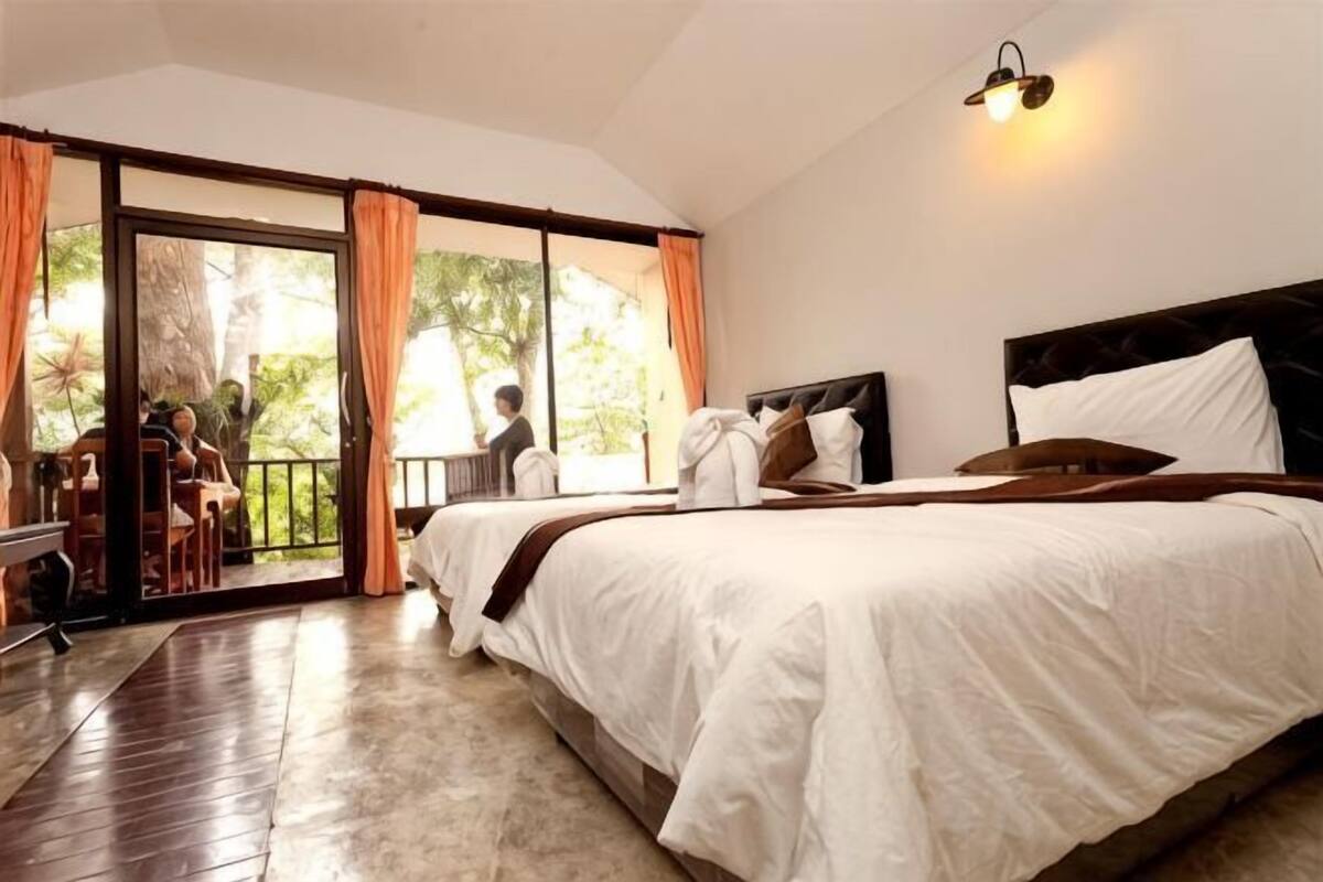 A bedroom with a bed, a desk, and a view through a sliding door to an outdoor area.