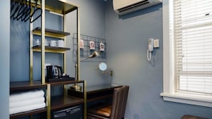 A compact hotel room with a desk, chair, and shelves. There is a coffee maker, a mirror, and a phone on the wall. - The Maisonette (Potts Point)