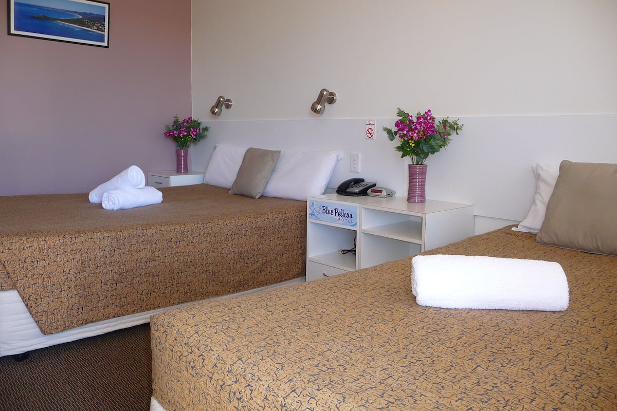 A hotel room with two beds, a desk, a phone, and a sign indicating the hotel name.