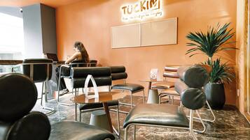 Un interior moderno con sillones de cuero negro, una mesa de centro, una planta en maceta y un letrero que dice 'TUCKIN'.
