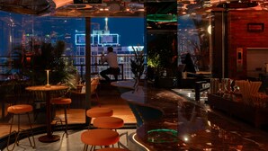 Uma área de bar com bancos, balcão e vista para o horizonte noturno.