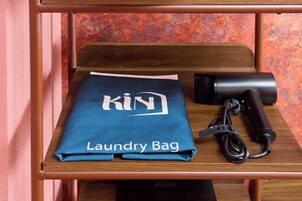 A wooden table with a blue laundry bag labeled "KIN Laundry Bag" and a black hairdryer.