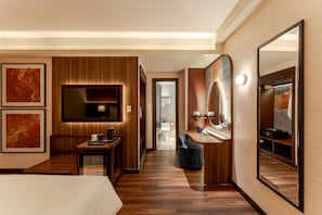 A hotel room with a wooden floor, a bed, a desk, a chair, a TV, a mirror, and artwork on the walls. - KiN Hotel Ly Tu Trong Edition (Ho Chi Minh City)
