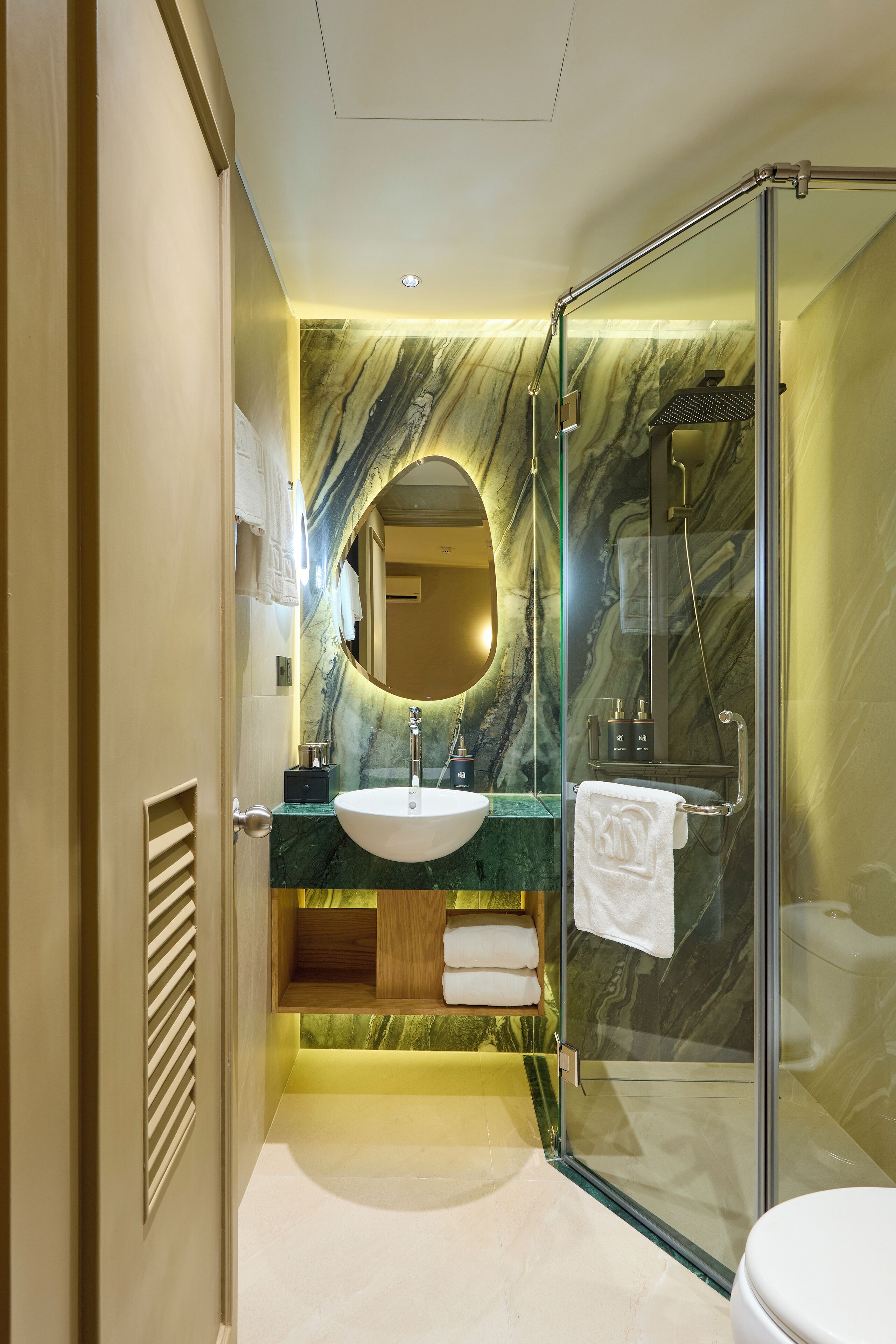 A modern bathroom with a marble vanity, a glass shower enclosure, and a toilet.