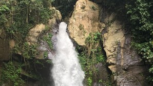 Une personne assise sur un rocher devant une cascade.
