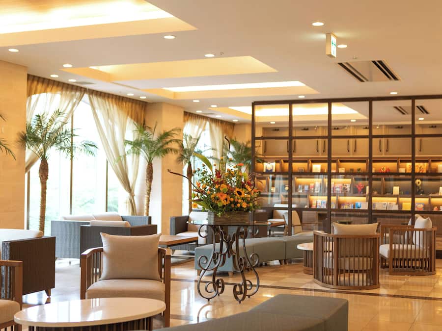 Un vestíbulo de hotel con zonas de estar, un arreglo floral y una estantería.