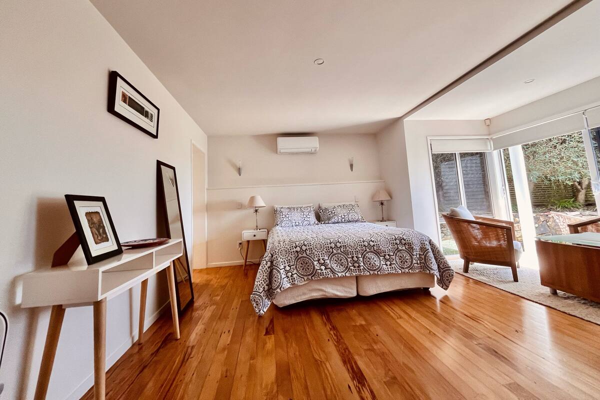A bedroom with a bed, bedside tables, a chair, and a large window.